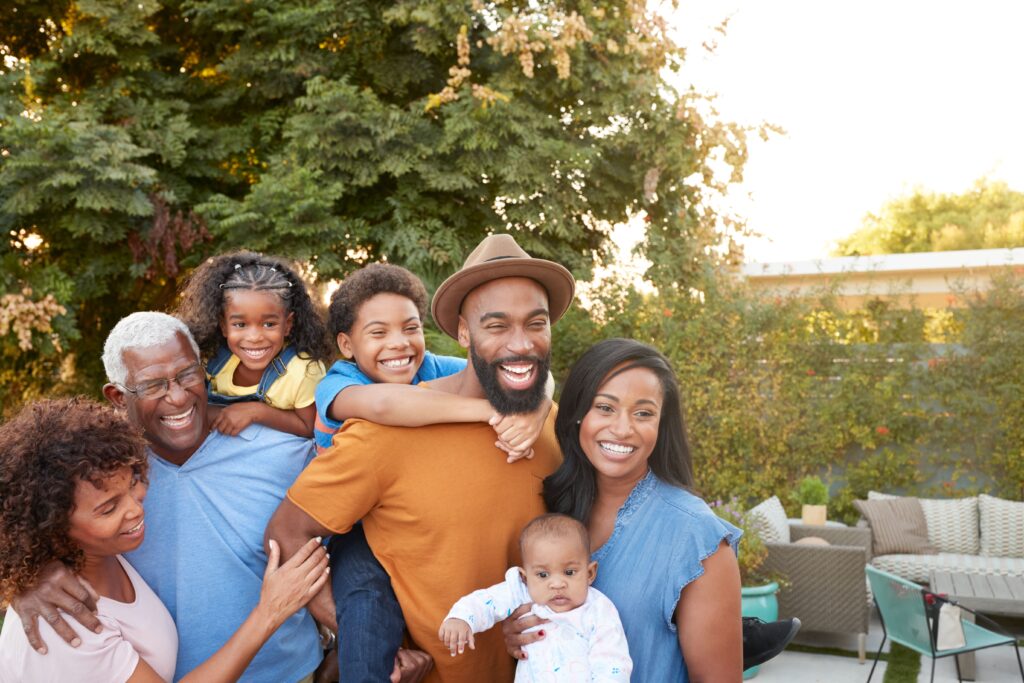 Smiling multi-generational family outdoors, representing employees at different life stages making benefits and open enrollment decisions.