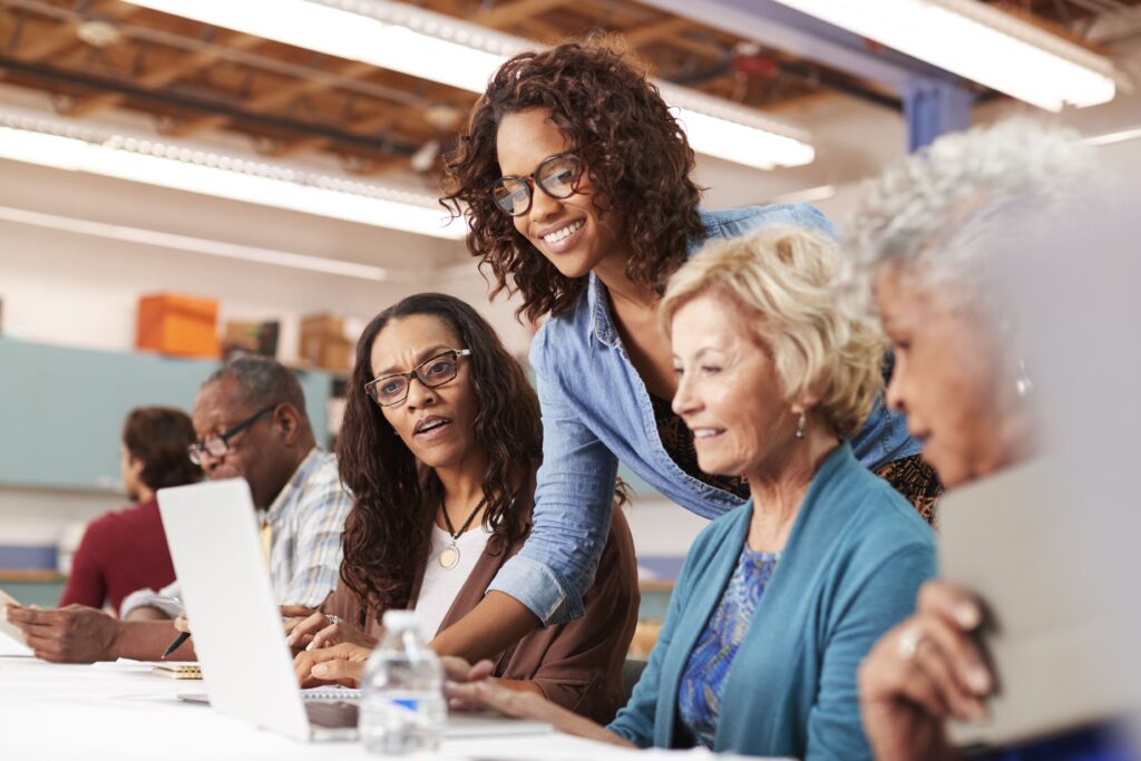 Diverse group of employees receiving guidance on laptops, symbolizing how wellness programs support open enrollment education and plan comprehension.