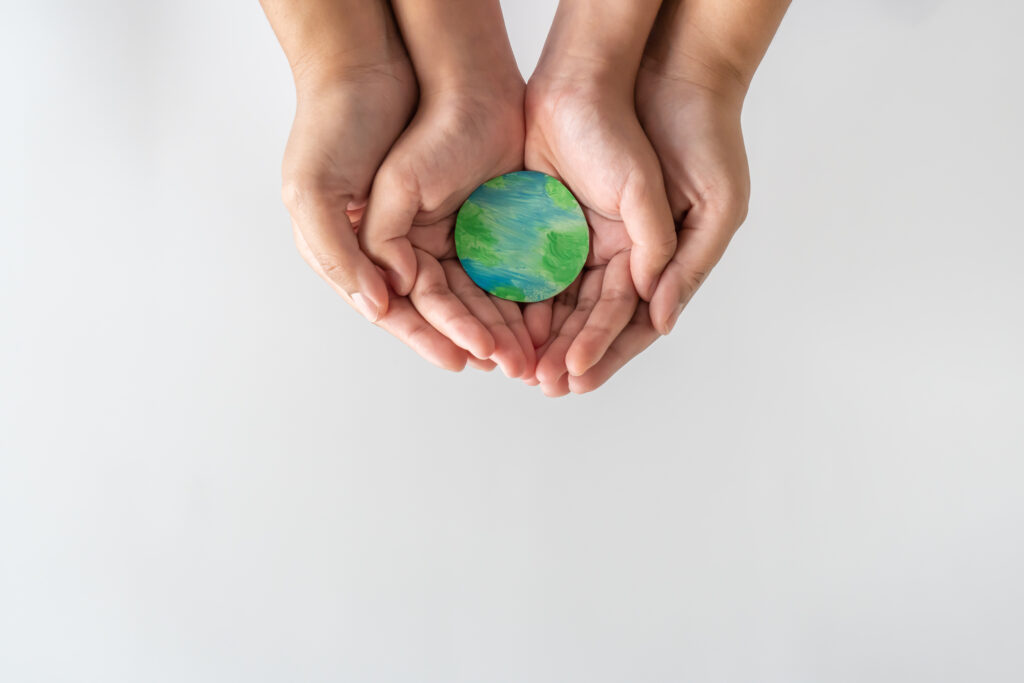 Adult and child hands gently holding a small Earth model, symbolizing global unity, care, and the importance of supporting mental health for all.