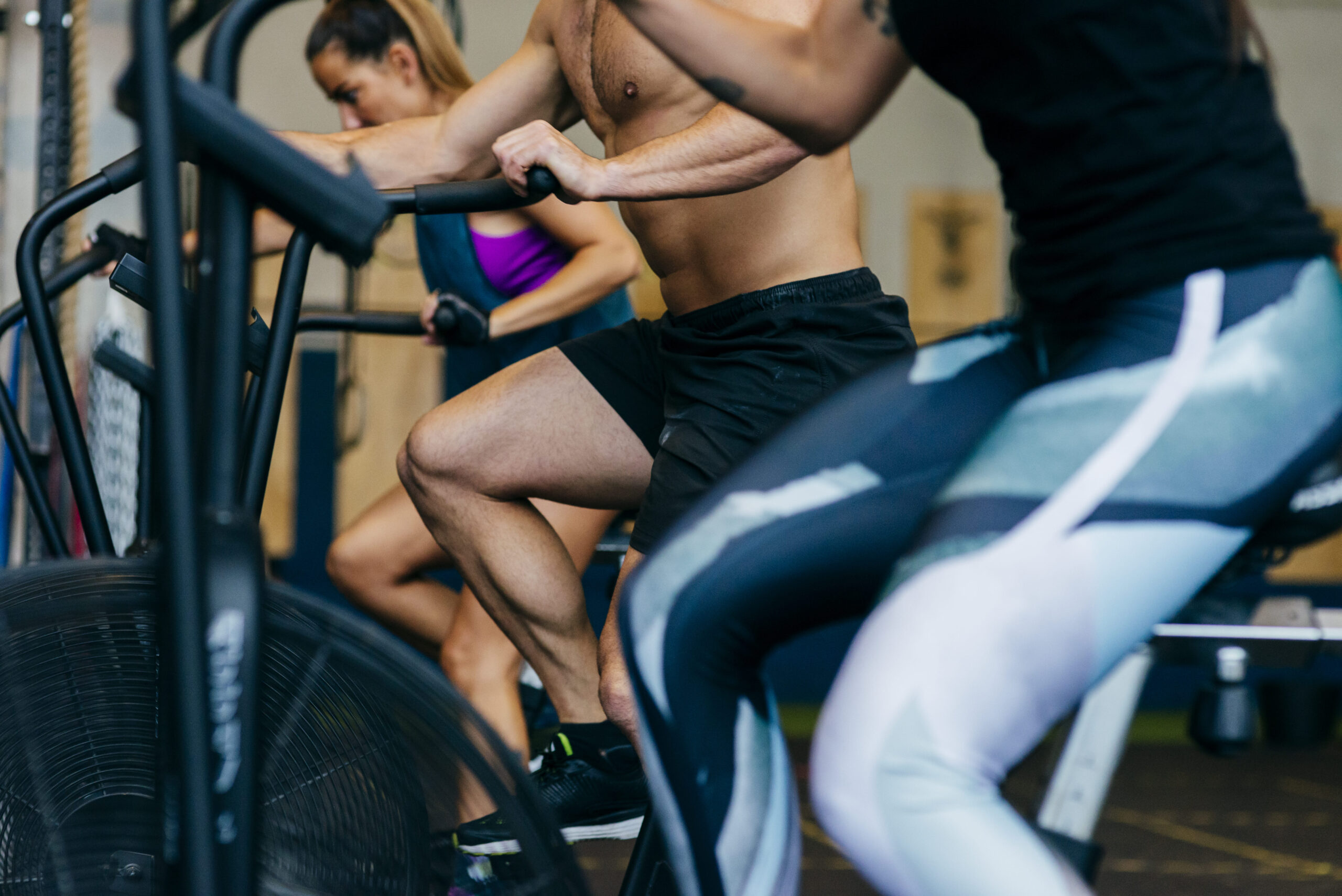 Employees participating in a cardio-focused workout on air bikes, highlighting the role of physical activity in improving cardio-metabolic health and reducing employer healthcare costs.