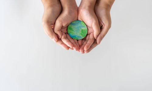 Adult and child hands gently holding a small Earth model, symbolizing global unity, care, and the importance of supporting mental health for all.