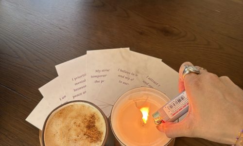 A stack of affirmation cards on a desk surrounded by plants and notebooks, symbolizing mindfulness, positivity, and workplace wellbeing.