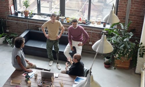 Small team of diverse startup employees engaged in a casual, collaborative meeting in a modern loft office—symbolizing early-stage company culture and open communication before scaling.